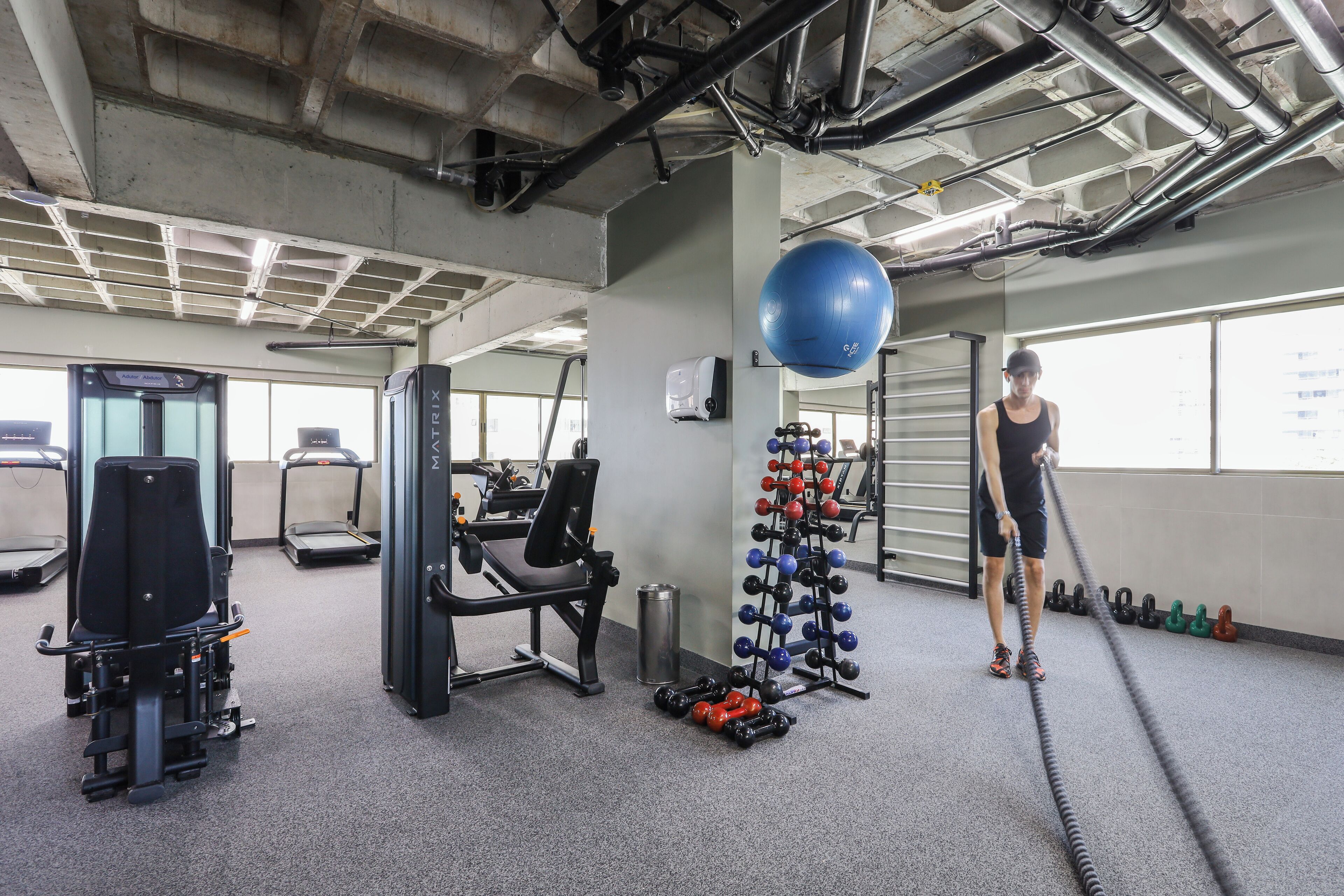 Une salle de sport équipée de matériel d’exercice, de tapis de course et de supports pour les poids.