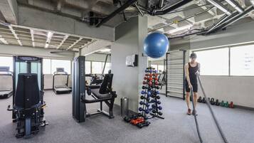 Une salle de sport équipée de matériel d’exercice, de tapis de course et de supports pour les poids.