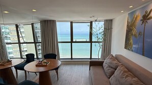 Una sala de estar moderna con un ventanal grande con vistas al mar, una mesa de comedor redonda y un sofá cómodo.