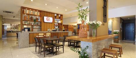 A modern hotel lobby with a bar area, seating arrangements, and a reception desk.