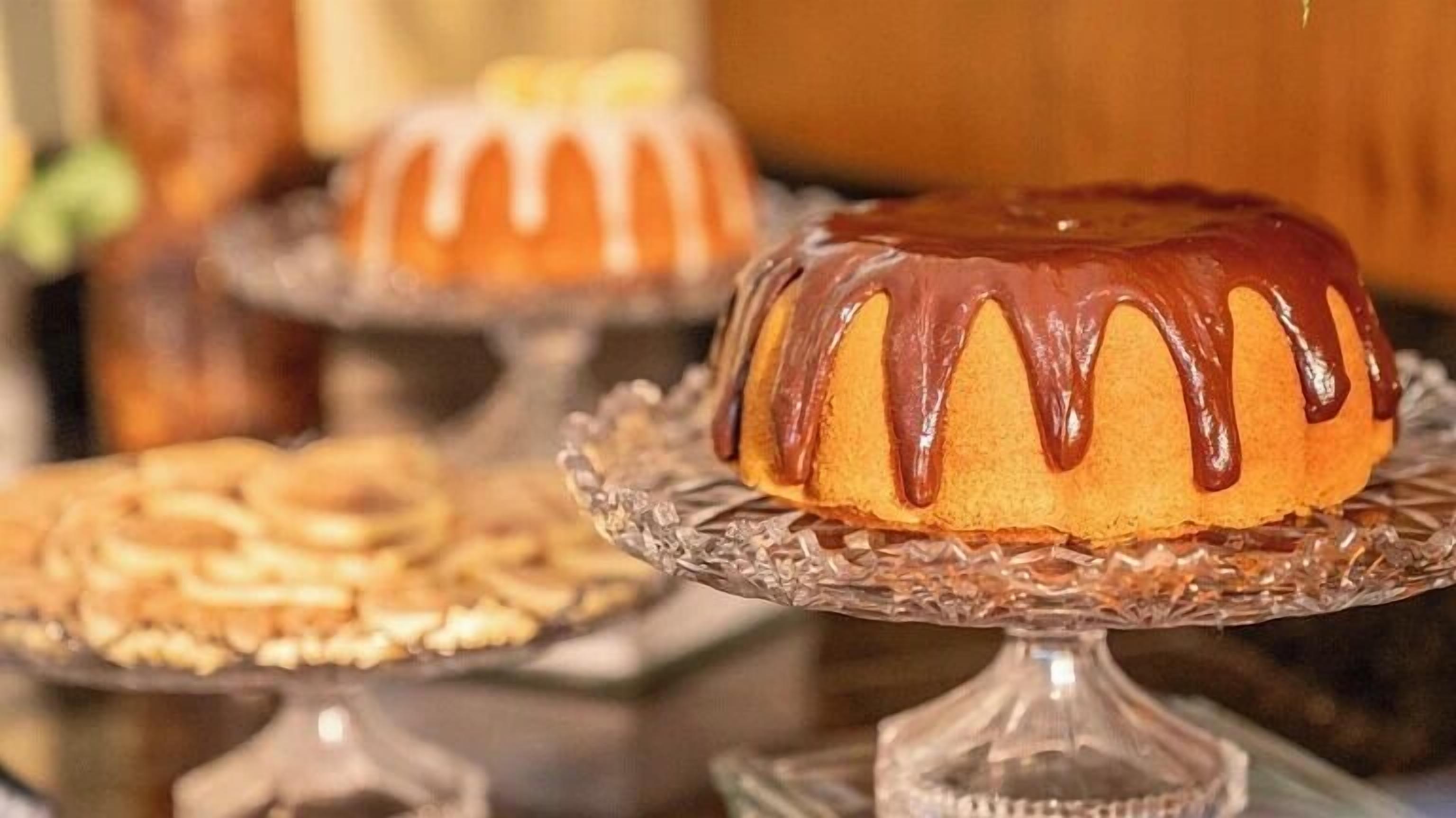 A bundt cake with chocolate glaze on a glass cake stand.