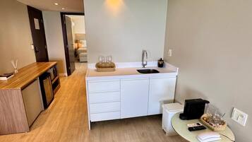 A compact kitchen with a sink, a small table with a phone and charger, and a wooden counter.