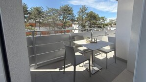 A balcony with a table and chairs, overlooking a residential area with trees and buildings. - Elegant and Luminous Apartment With Terrace (San Michele al Tagliamento)