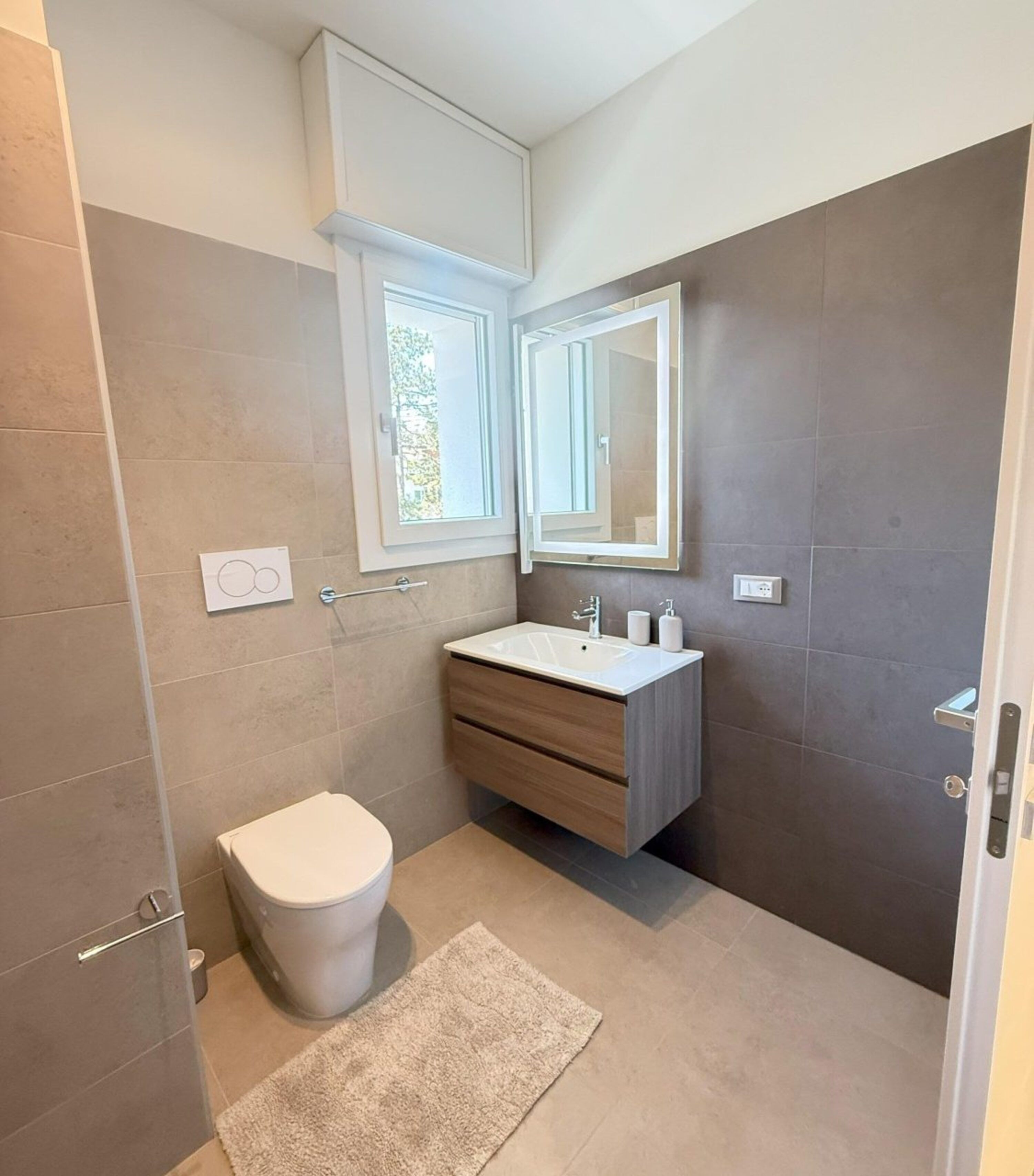 A modern bathroom with a toilet, sink, and mirror.