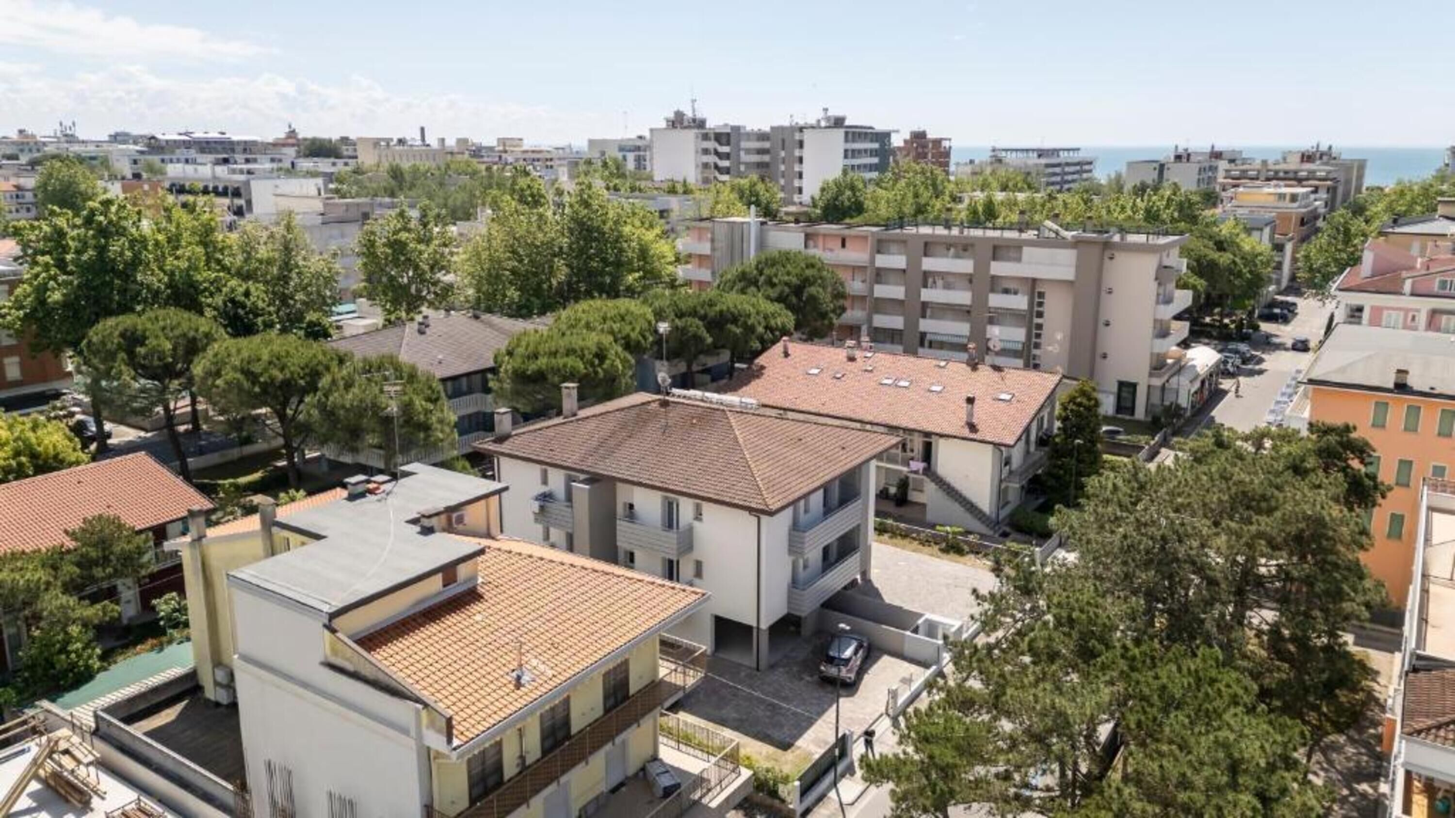 A residential area with modern buildings, a parking lot, and a view of the sea.