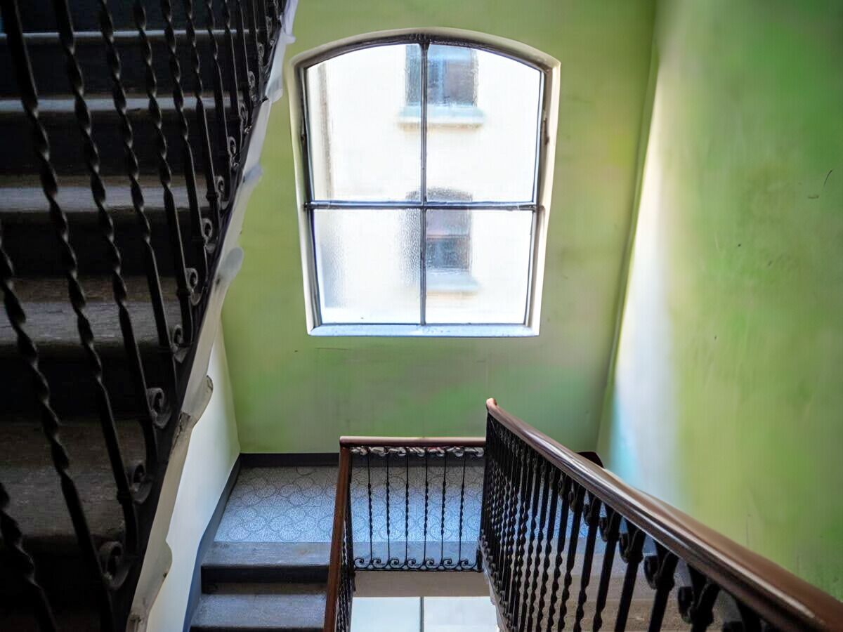 A staircase with a wooden handrail and a window with a grid pattern.