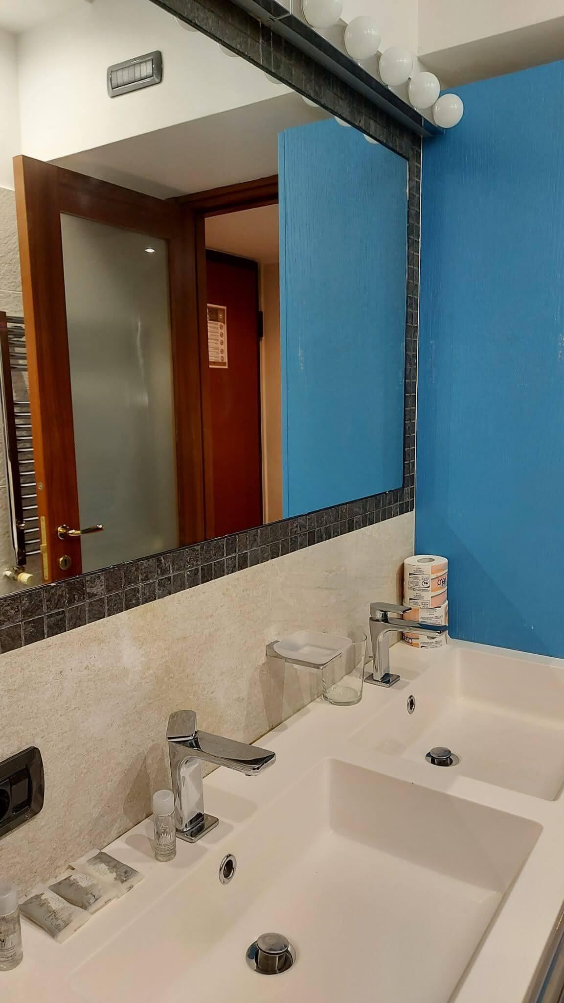 A bathroom with a white sink, a mirror, and a blue wall.