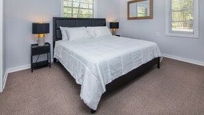 A bedroom with a large bed, two bedside tables with lamps, a mirror, and two windows with blinds. - Peaceful 1BR Apartment for Extended Stays in Huntersville (Huntersville)