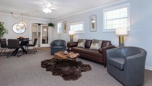 A modern living room with a brown leather sofa, two grey armchairs, a wooden coffee table, and a shaggy rug. - Peaceful 1BR Apartment for Extended Stays in Huntersville (Huntersville)
