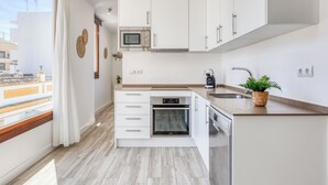 Een moderne keuken met witte kastjes, een magnetron, oven en vaatwasser.