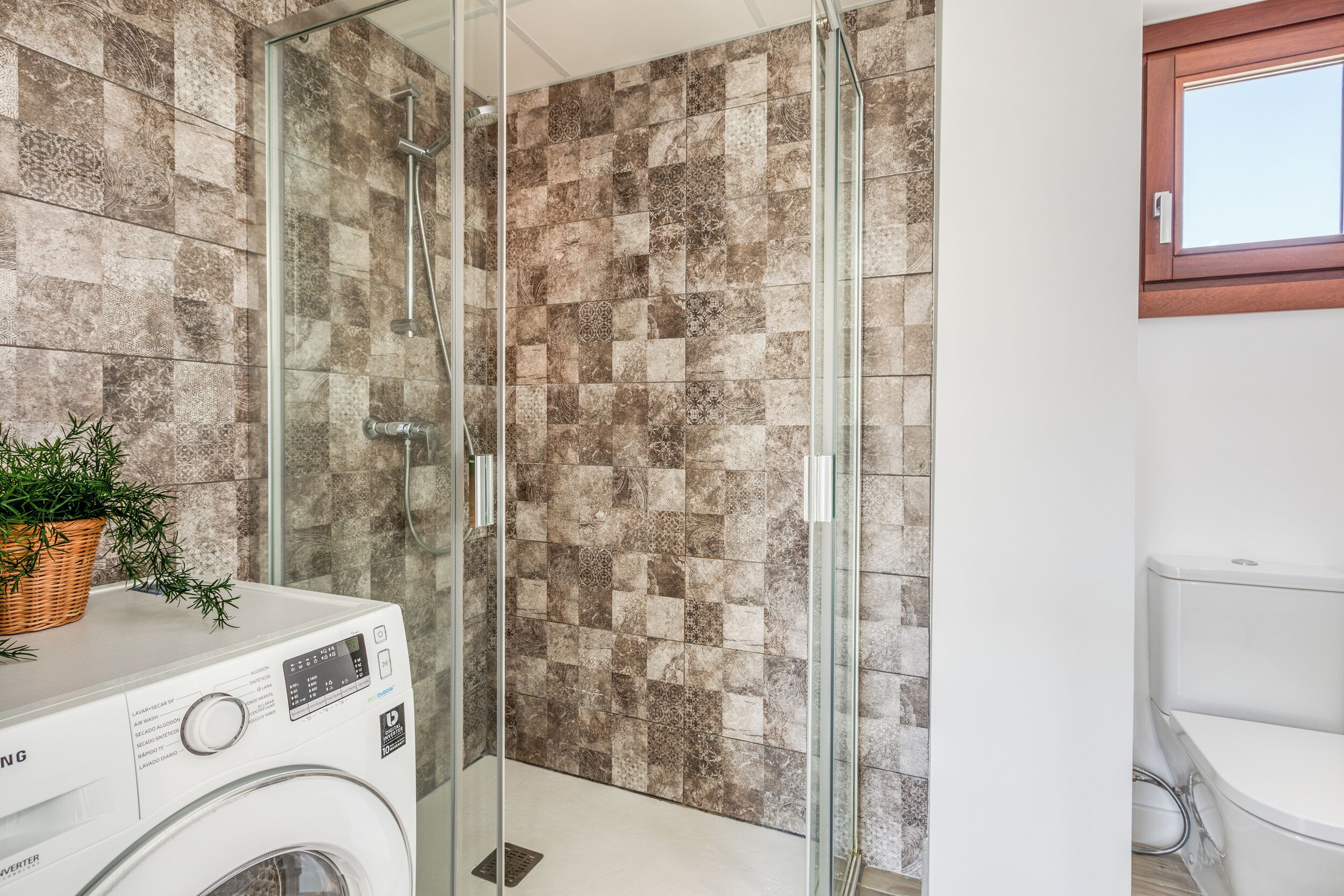 Un bagno moderno con doccia vetrata, lavatrice e servizi igienici.