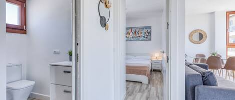 A modern apartment with a bathroom, a bedroom with a bed and nightstand, a dining area with a table and chairs, and a living area with a sofa and a coffee table.