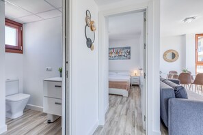 A modern apartment with a bathroom, a bedroom with a bed and nightstand, a dining area with a table and chairs, and a living area with a sofa and a coffee table. - Apartamentos Donato Vista Mar by Croma (Estepona)
