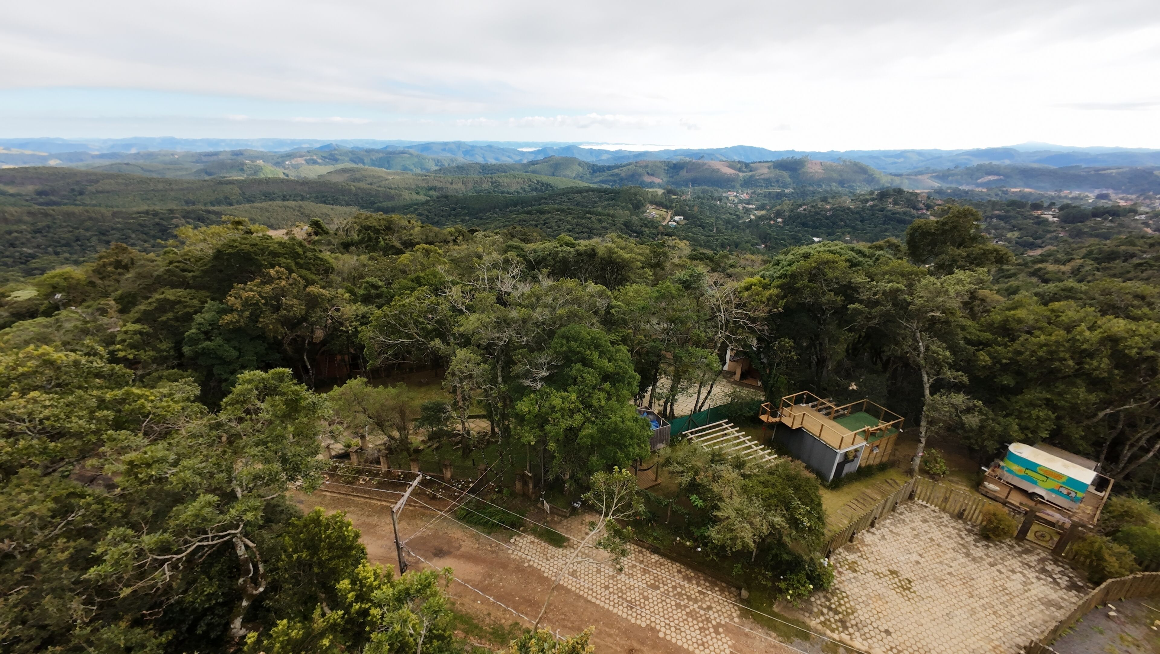 Vista aérea desde gran altura de un área boscosa con un pequeño edificio rodeado de árboles.