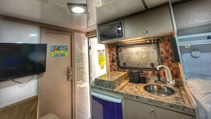 A compact kitchenette with a microwave, sink, and small countertop. - Recanto lira 2  (Monte Verde)