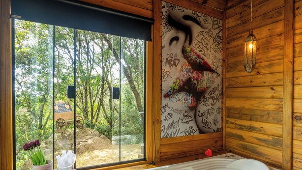 A wooden cabin with a large window, a hot tub, and a small table with flowers. - Recanto lira 2  (Monte Verde)