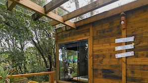 A wooden deck with two yellow chairs and a window. - Recanto lira 2  (Monte Verde)