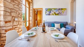 Un comedor con pared de piedra, mesa de madera y un sofá.