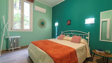 Ein Schlafzimmer mit einem Bett, einem Heizkörper, einem Fenster und einer Wandleuchte.