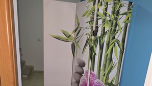 A room with a blue wall, a white door, and a decorative bamboo and orchid panel. - Apartment only 200mt from the beautiful beach Private parking (Torre San Giovanni)