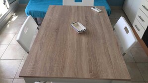 A wooden table with chairs, a blue bed, and a white bedside table with a phone. - Apartment only 200mt from the beautiful beach Private parking (Torre San Giovanni)