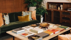 A modern living room with a green sofa, a coffee table with books, a potted plant, and a decorative lamp. - Charleston Suite | 2 King Beds + Luxe Interiors (Charleston)