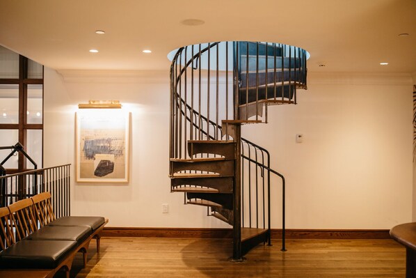 A spiral staircase with metal railings, wooden steps, and a glass enclosure at the top.