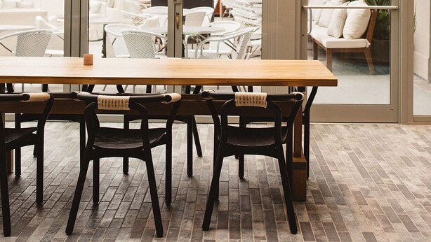 Un espace repas avec une longue table, des chaises noires et un luminaire suspendu.