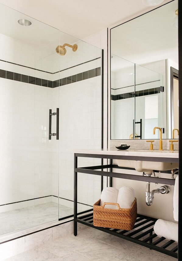 A modern bathroom with a glass-enclosed shower, a black metal vanity, and a large mirror.