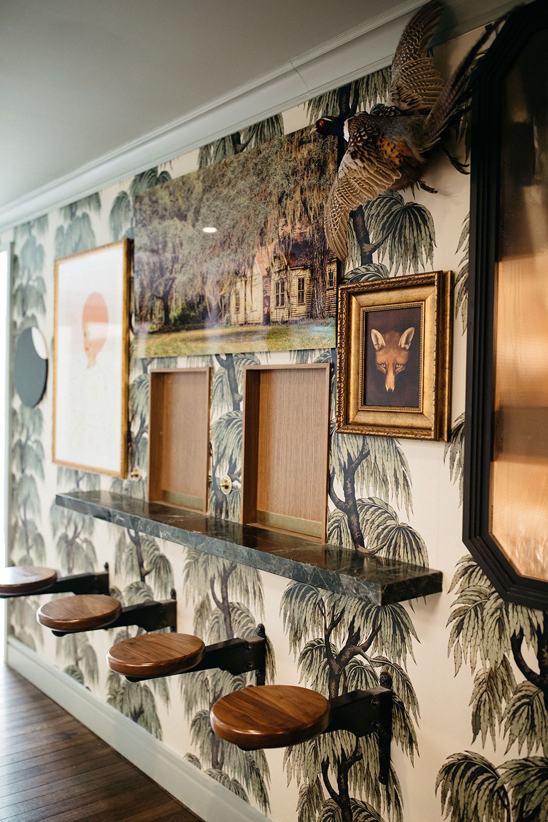 A bar area with a mural of trees and a framed fox picture.