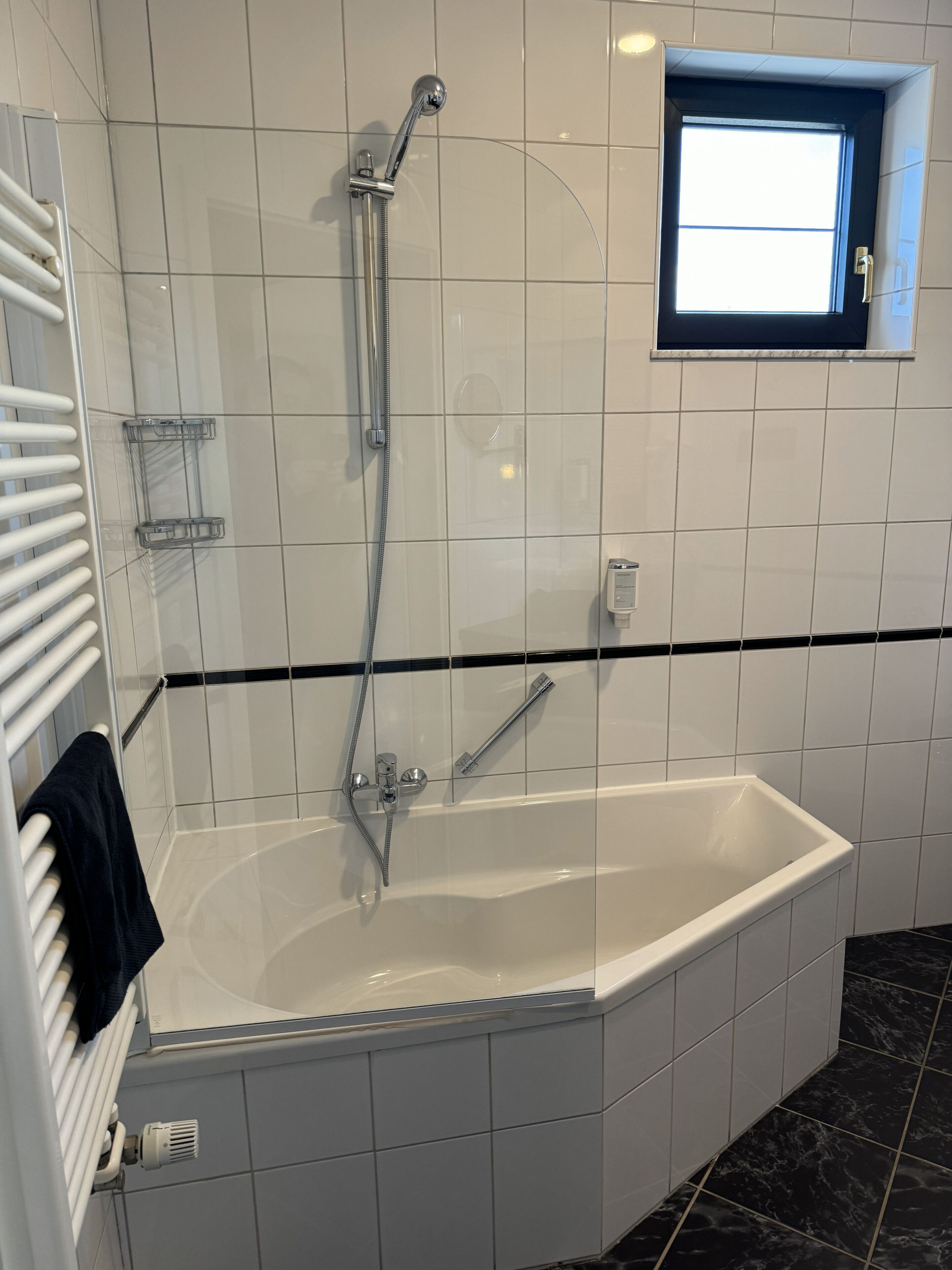 A modern bathroom with a freestanding bathtub, a handheld showerhead, and a towel rack.