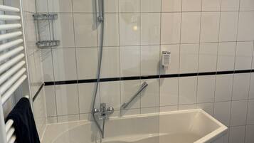 A modern bathroom with a freestanding bathtub, a handheld showerhead, and a towel rack.
