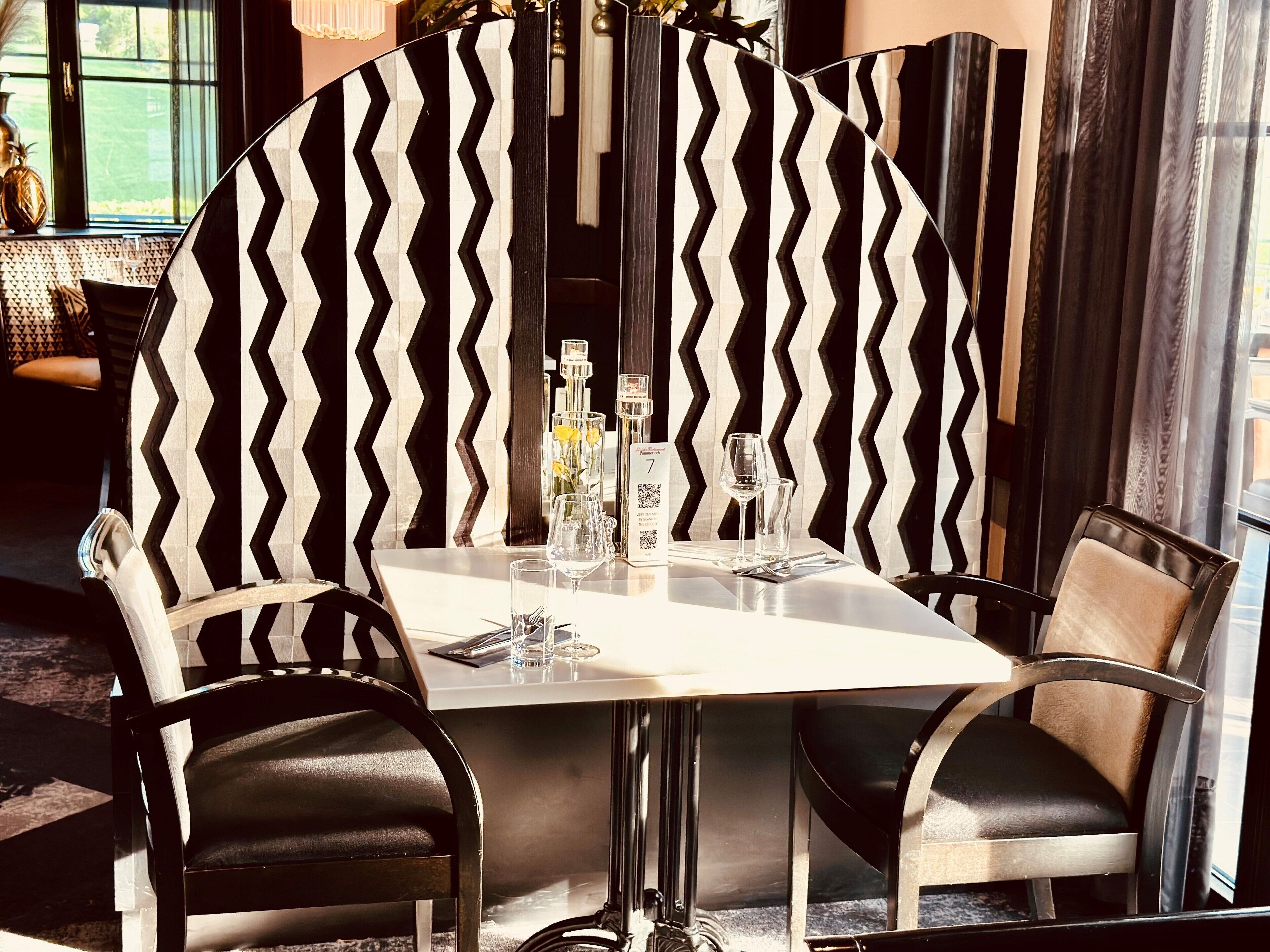 Un comedor con una mesa redonda, sillas de diseño blanco y negro y una decoración de interiores moderna.