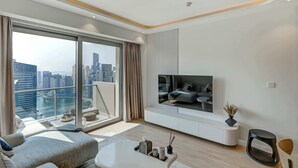 Un salon moderne doté d’un grand téléviseur, de sièges confortables et offrant une vue sur la ville.