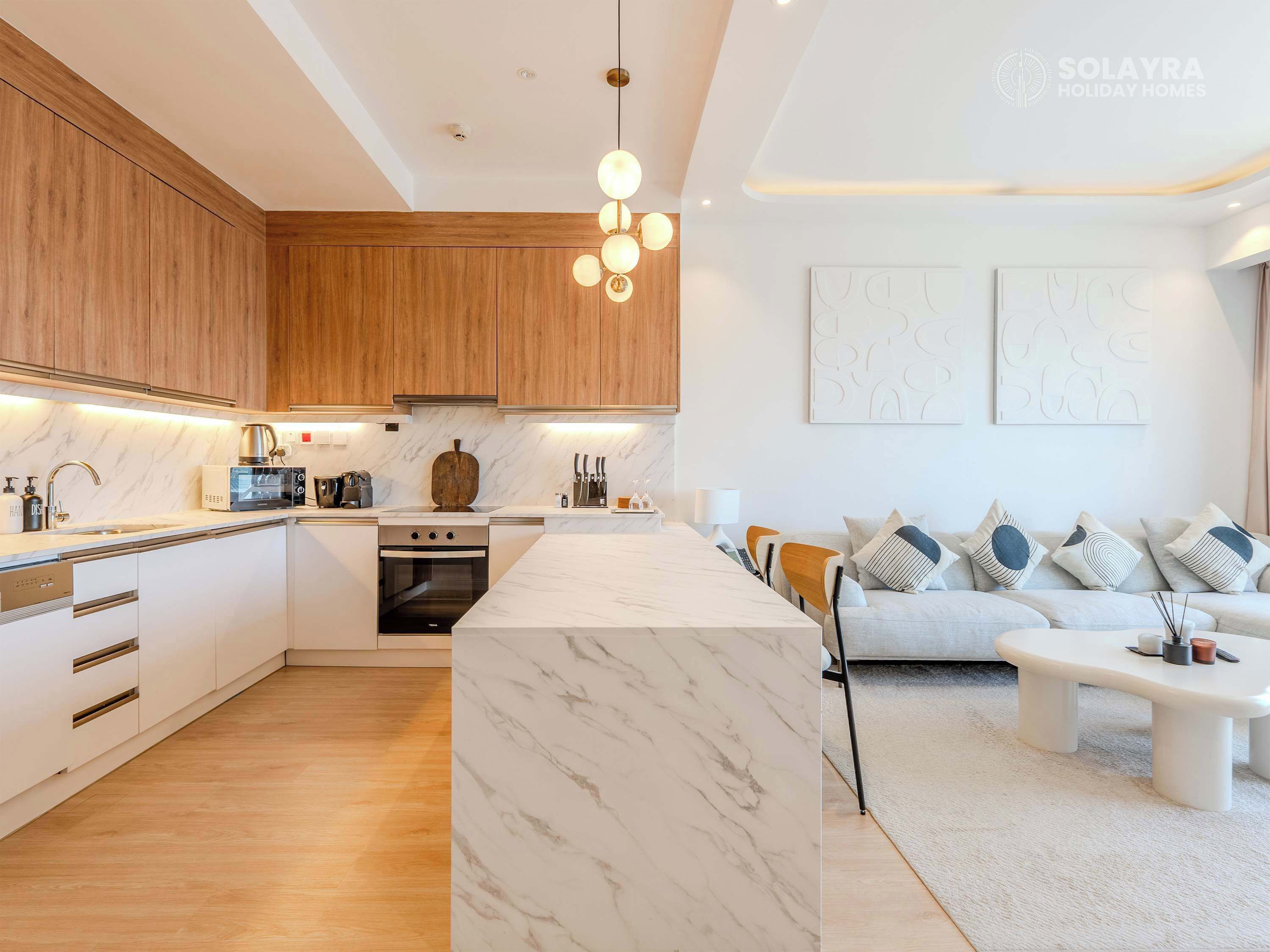 Une cuisine moderne avec des meubles en bois, un îlot en marbre et un coin repas comprenant un canapé et une table basse.