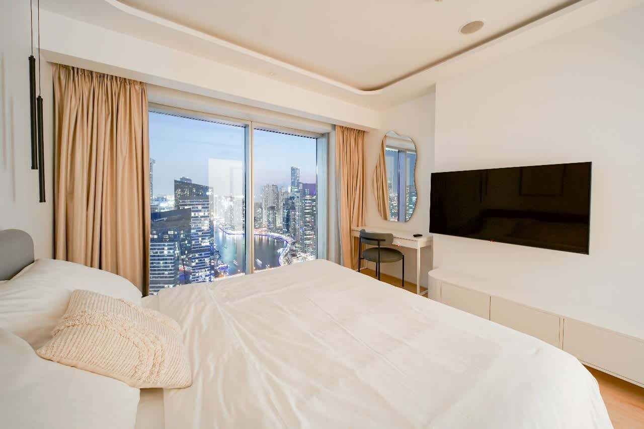Une chambre d’hôtel moderne, dotée d’un grand lit, d’un bureau et d’une télévision.