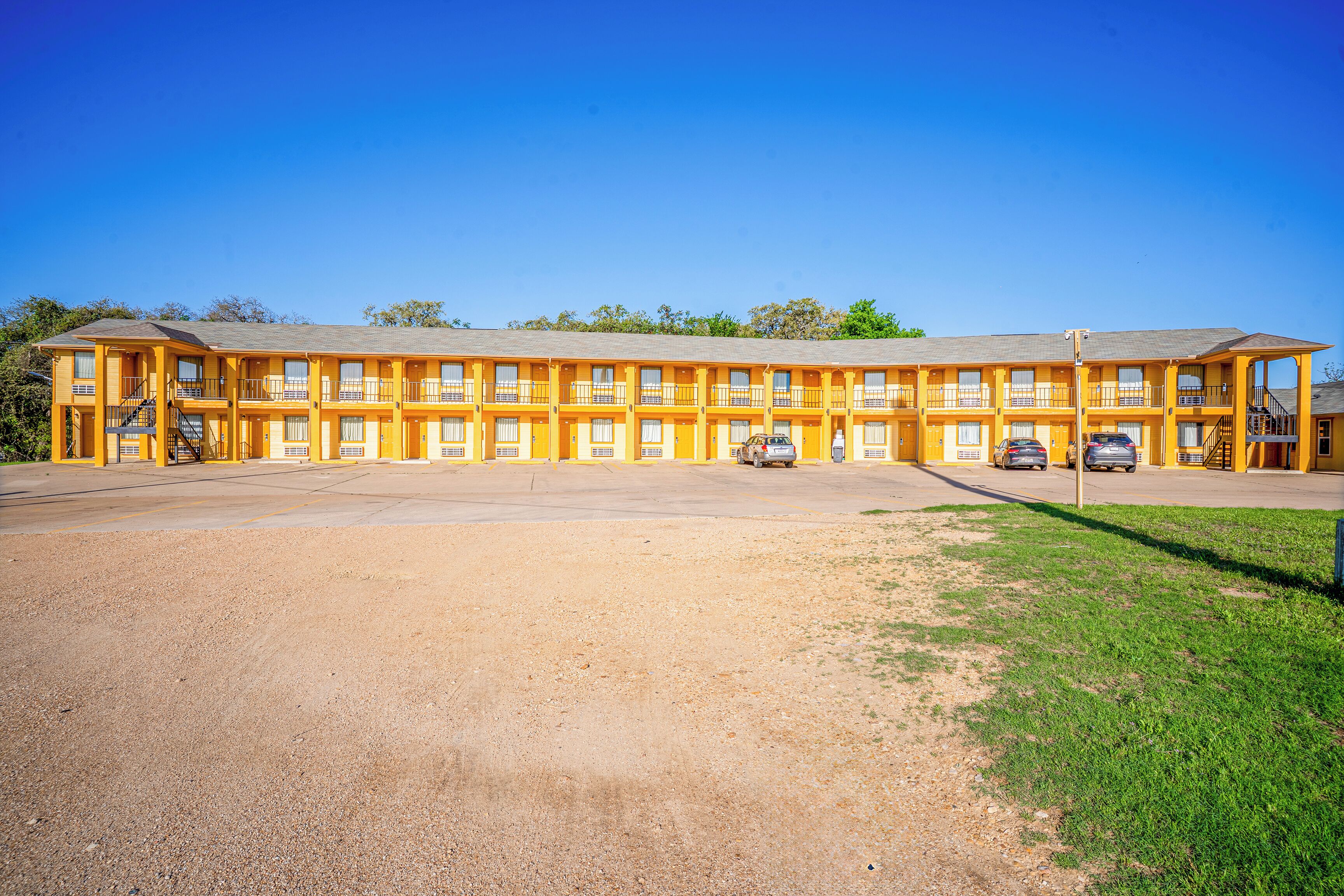 A motel with a central courtyard, multiple balconies, and a parking area.