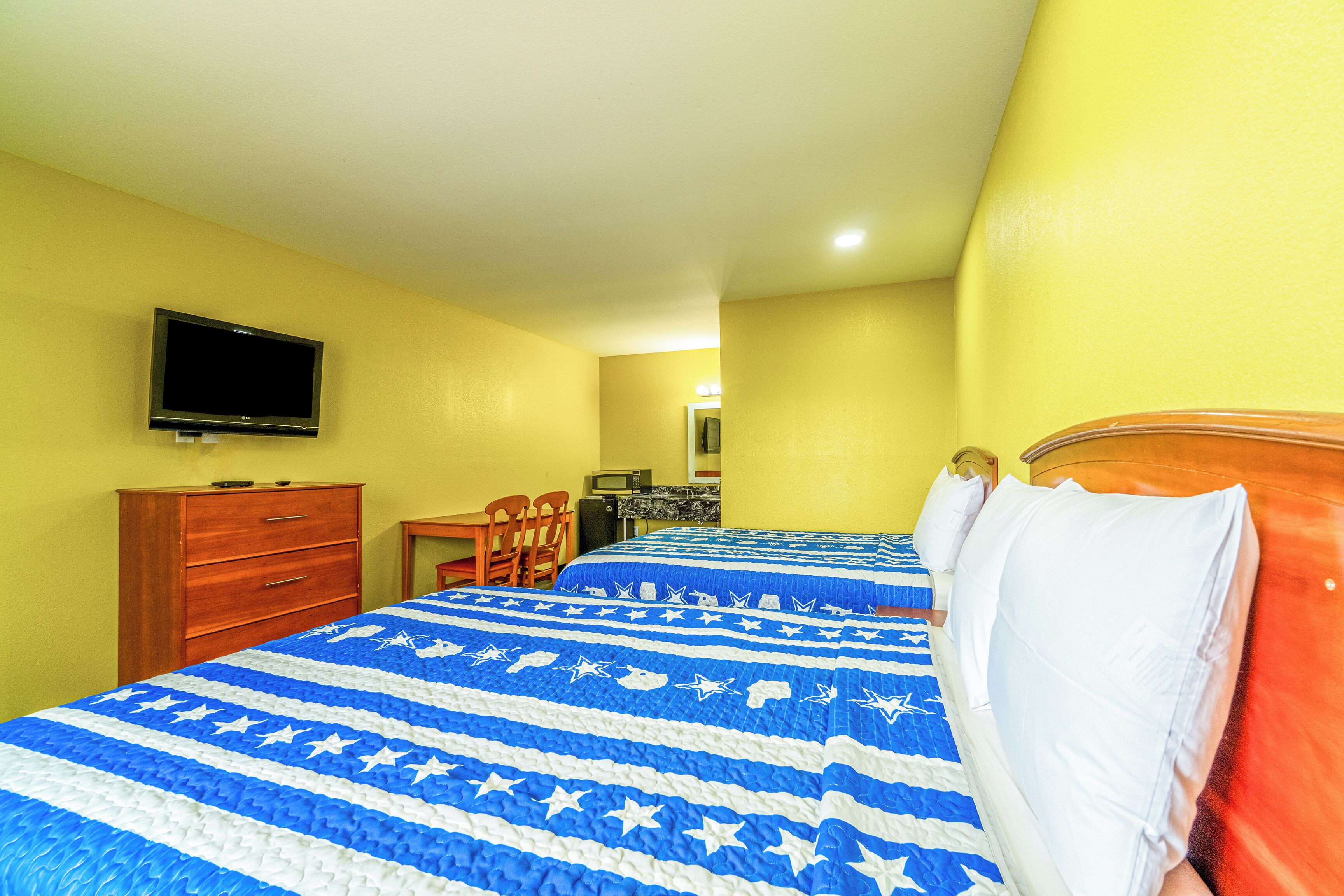 A hotel room with two beds, a TV, a desk, and a chair.