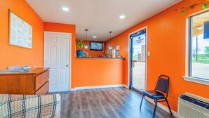 A room with orange walls, a wooden desk, a chair, a television, and a window. - Regency Inn By OYO Rockdale TX (Rockdale)