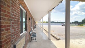 A covered outdoor area with a brick wall, benches, and a parking lot in the background. - Imperial Inn Tazewell (Tazewell)