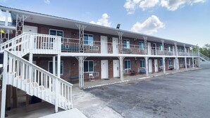 A motel with a central staircase, multiple balconies, and a parking lot. - Imperial Inn Tazewell (Tazewell)
