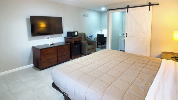 A bedroom with a bed, a TV, a desk, and a chair. - Imperial Inn Tazewell (Tazewell)