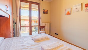 A bedroom with a bed, a chair, a window, and a view of the outside. - Garden Residence - Italian Homing (Desenzano del Garda)