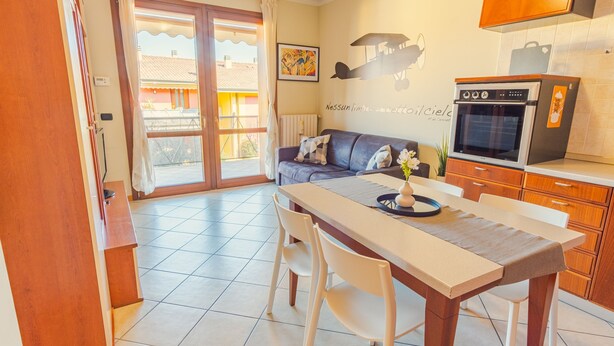 A modern kitchen with a dining area, featuring a large window, a sofa, and a refrigerator. - Garden Residence - Italian Homing (Desenzano del Garda)