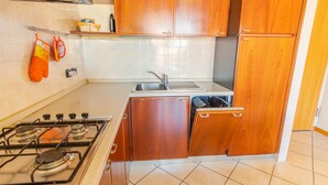 A compact kitchen with a gas stove, a sink, and a dishwasher. - Garden Residence - Italian Homing (Desenzano del Garda)