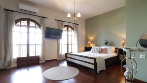 A bedroom with a bed, a flat-screen TV, a chandelier, a bedside table with lamps, and a decorative pitcher. - House Sea View with Communal Pool (Corfu)