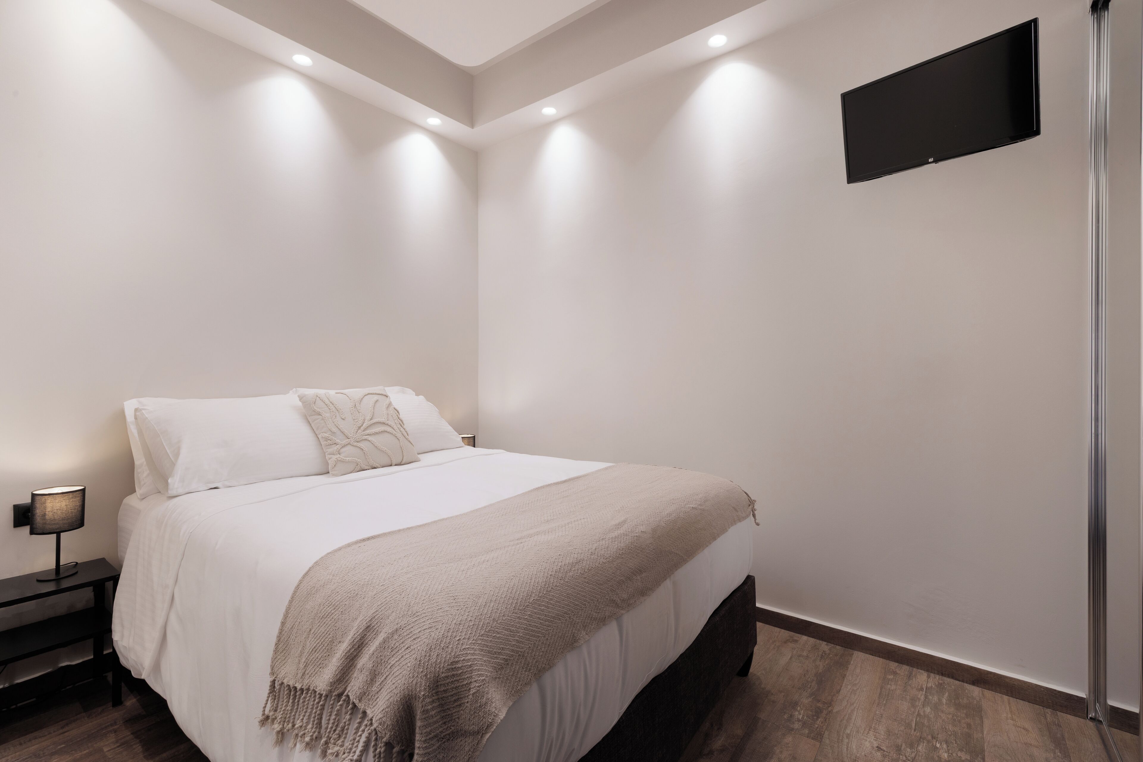 Une chambre à coucher moderne avec un lit, une lampe de chevet et un téléviseur fixé au mur.