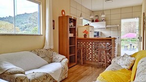 A cozy living room with a sofa, a wooden cabinet, and a kitchen area with a bar.