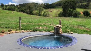A circular pool with a blue-tiled edge, surrounded by a concrete deck.