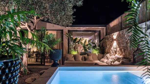 Un espace piscine extérieur moderne, doté d’un coin salon et d’une végétation luxuriante.
